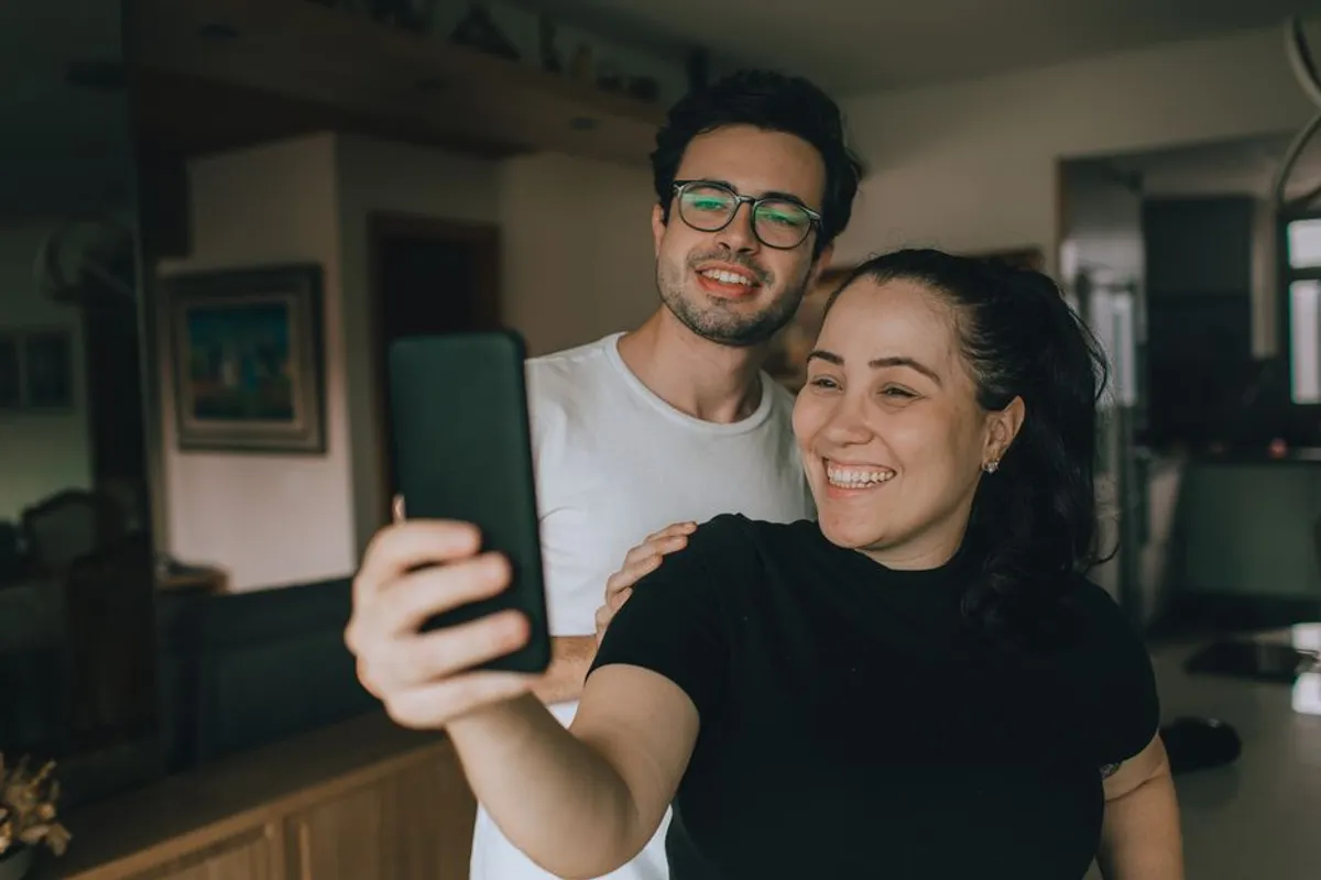 Couple smiling while using their phones together