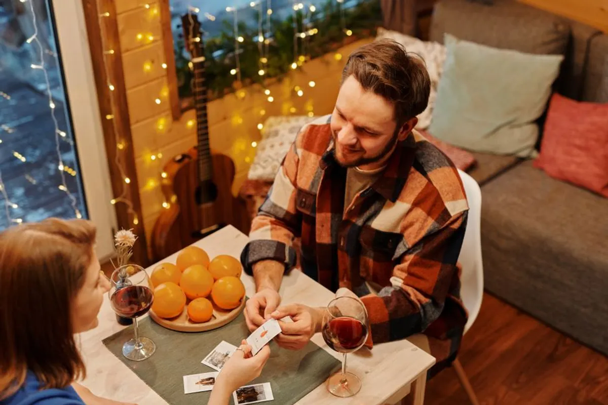 Couple sitting at a table with cards and a warm drink in the evening
