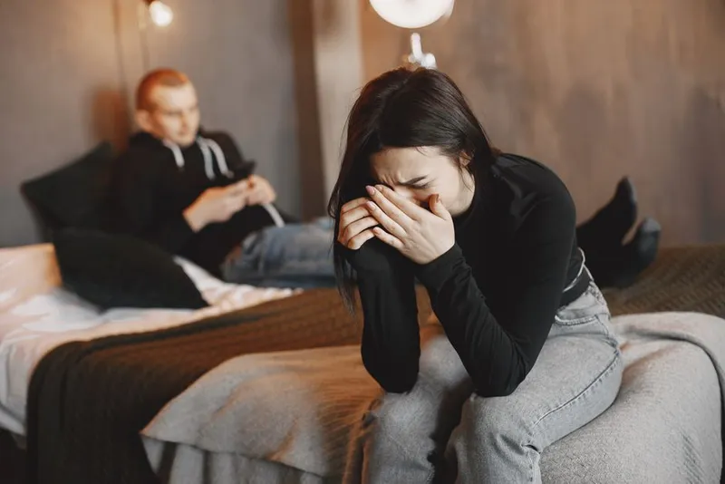 Couple lying apart in bed, quiet and distant in soft light