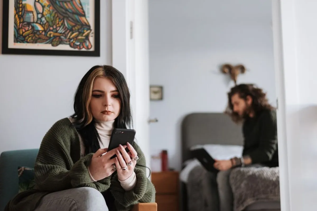 Two people looking at their phones in a comfortable home setting