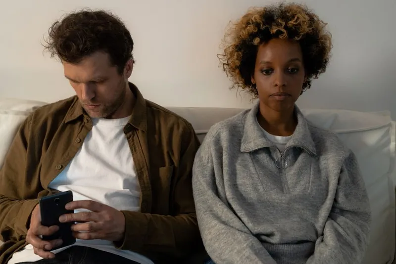 Couple sitting apart on a sofa in quiet evening light